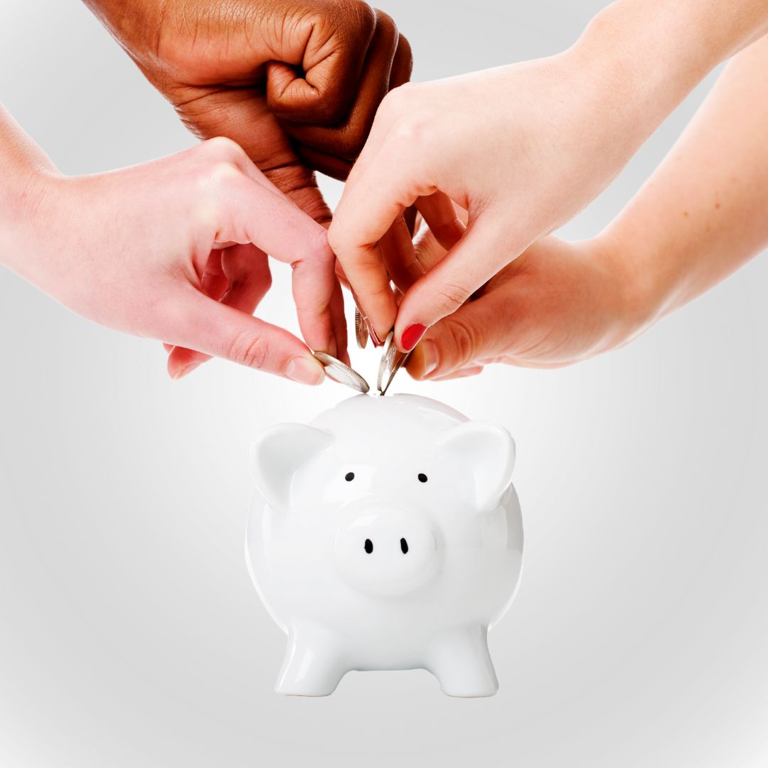 Hands putting coins into a pig-shaped piggy bank