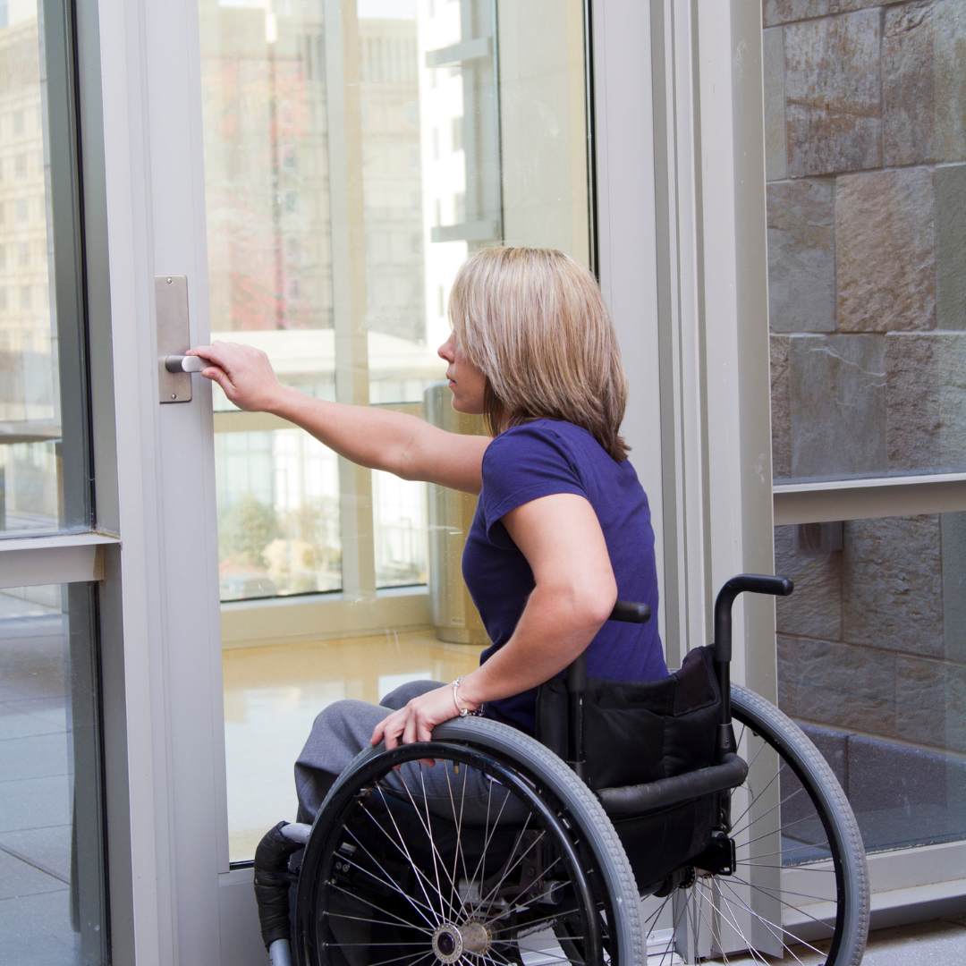 Woman in a wheelchair trying to open a door
